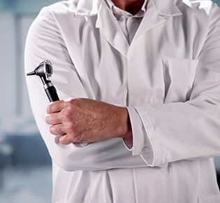 person in white coat holding an otoscope