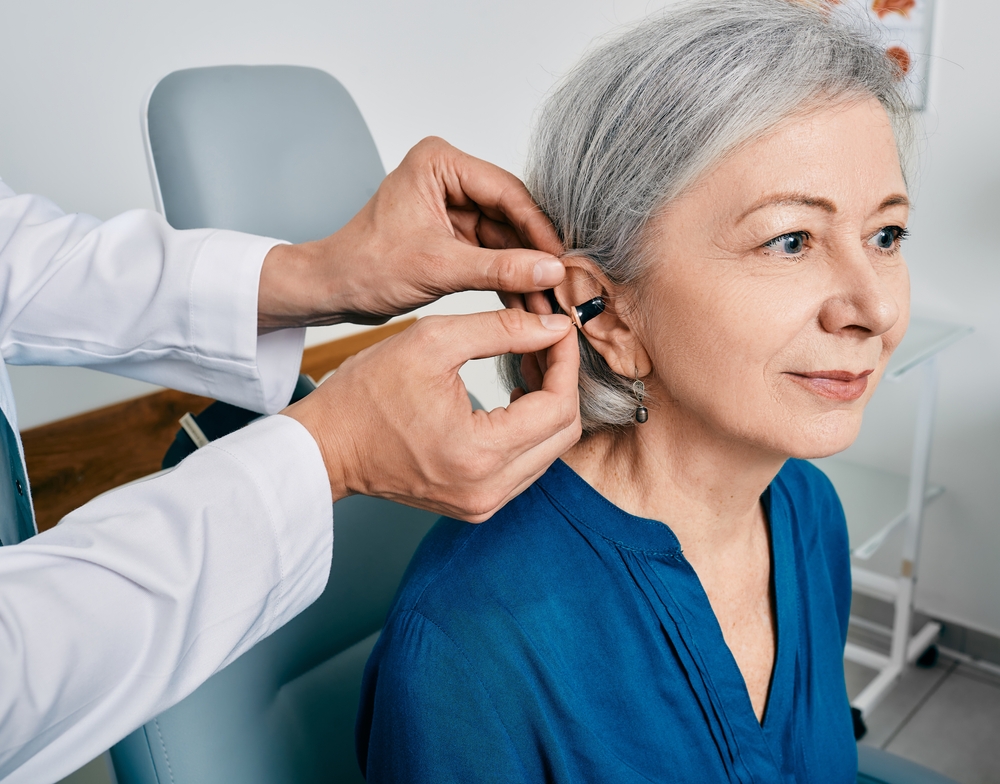 woman getting hearing aid installed