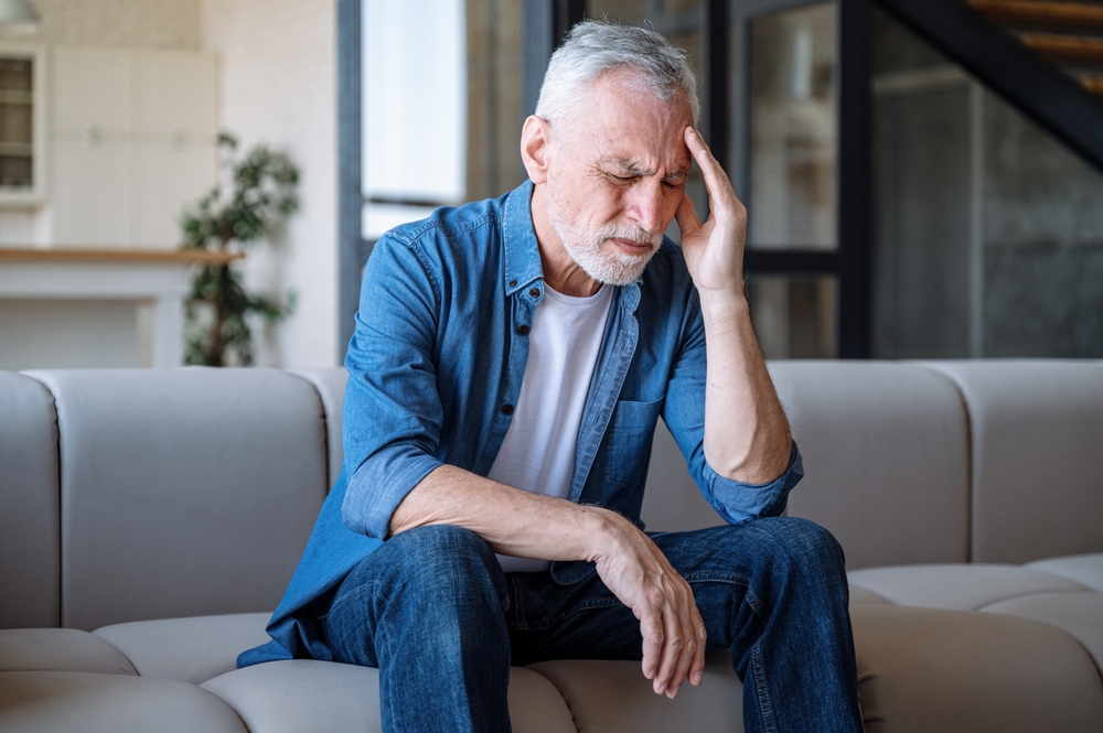 man sitting on sofa with a headache