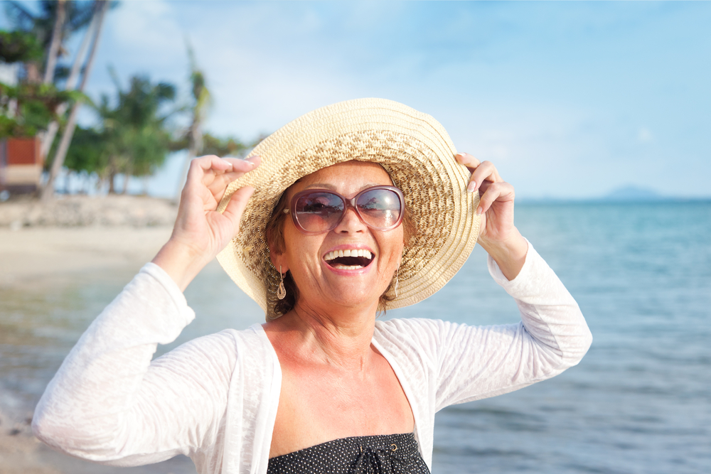 happy woman on the beach holding her hat